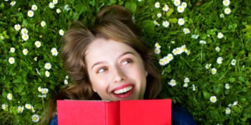 woman reading a book outside in the grass